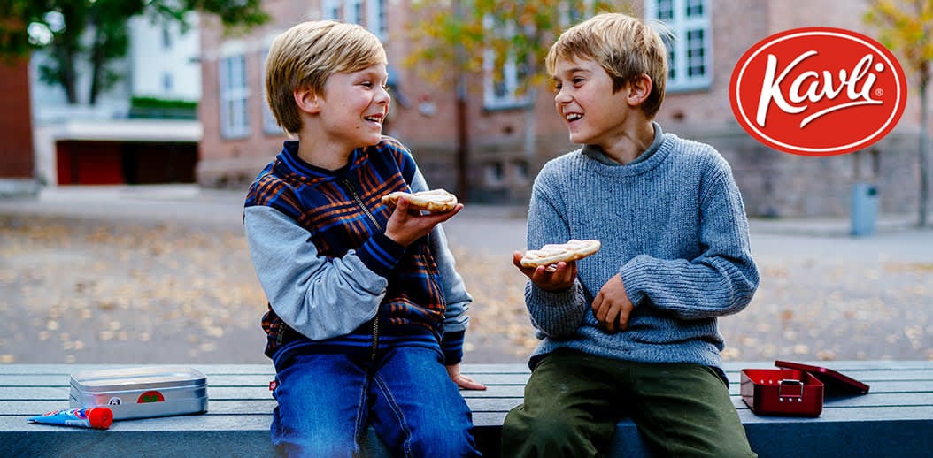 Image of two kids eating sandwiches on a bench.
