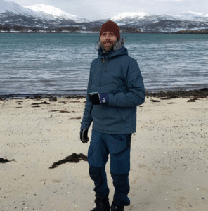Person vinterlig kledd på en stranden i nord-norge