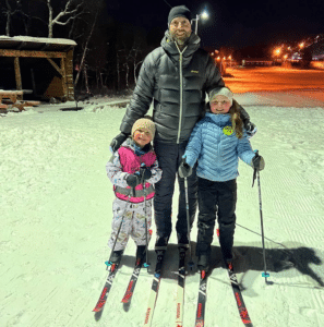 Far med to barn på skitur