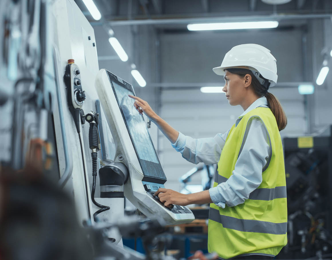 En operatør følger med på et kontrollpanel i et industrielt produksjonsmiljø.